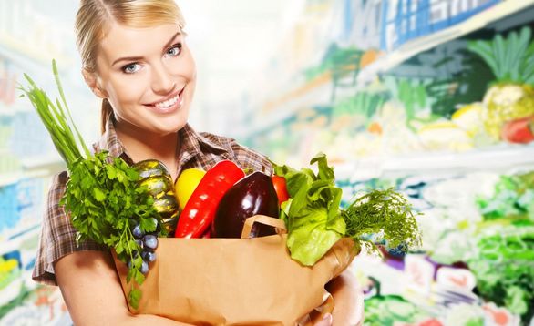 Frau in Supermarkt mit Einkaufstüte, gefüllt mit gesunden Lebensmitteln