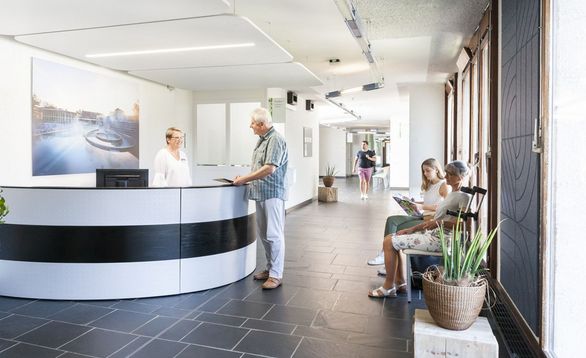Mitarbeiterin begrüsst Patient am Therapie-Empfang