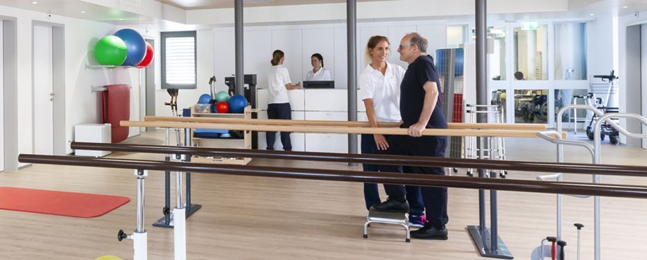 Therapeutin übt mit Patient in MTT-Raum an Geräten